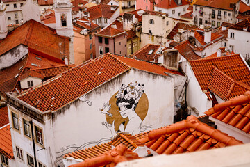 Streetart mural on a building in old town of Lisbon, Portugal with a view over the rooftops
