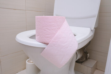 A pink piece of toilet paper standing on a seat of a toilet bowl, digestive problems and defecation disorder concept