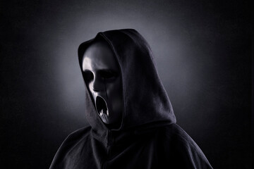 Ghostly figure in hooded cloak in the dark