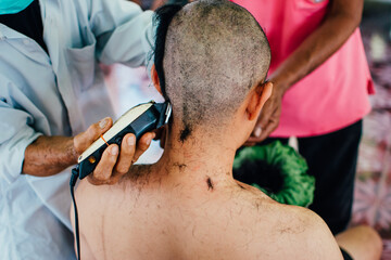 
Close up of Asian man shaving hair for Buddhist ordination ceremony in Thailand. Preparation for new Thai monk.