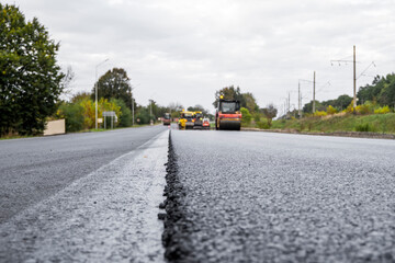 Asphalt road roller with heavy vibration roller compactor press new hot asphalt on the roadway on a road construction site. Heavy Vibration roller at asphalt pavement working. Repairing.