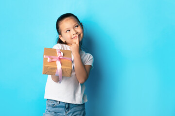 Happy girl holding gift box at blue studio