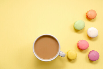 Obraz na płótnie Canvas Set of colorful macaroons and coffee. Pastries, pastries and a cup of coffee with milk on a yellow background. Confectionery. good morning. Copy space. view from above.