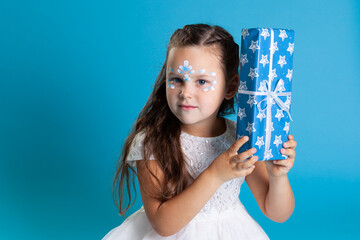 close up girl in a white dress and makeup on her face shakes the box in front of her face and guesses what's in there, copy space.