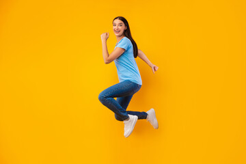 Fototapeta na wymiar Happy woman jumping over yellow studio wall