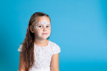 close up portrait of a girl in a white Christmas dress with a gentle smile isolated on a blue...