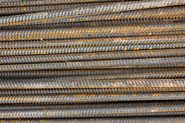 Many steel bars are laid horizontally. Rust is visible on the ribbed metal surface. Background. Texture.