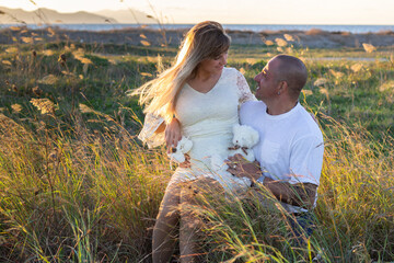 Happy pregnant couple in countryside on sunset - 389734535