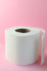 Soft roll of white toilet paper on pink background
