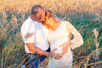 Husband with his pregnant wife outdoors on sunset 