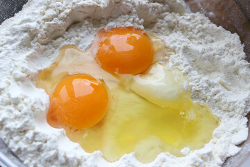 A bowl of flour and egg on the kitchen table.Preparation of home-made dough. Baking ingredients