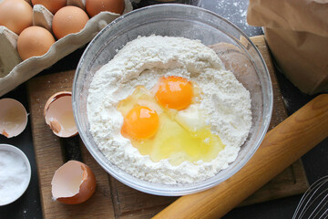 A bowl of flour and egg on the kitchen table.Preparation of home-made dough. Baking ingredients