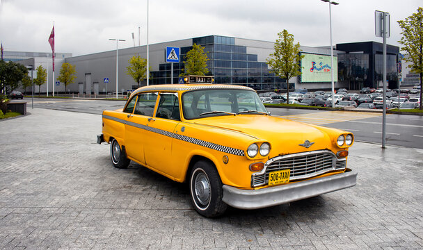 Yellow, old, vintage taxi car in front of Vegas Mall in Moscow. Crocus Expo (exhibition center) is in the background.