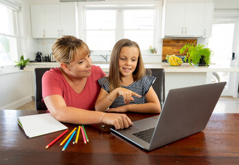Fototapeta na wymiar Mother and happy daughter studying at home during coronavirus self isolation and school closures