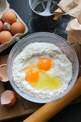 A bowl of flour and egg on the kitchen table.Preparation of home-made dough. Baking ingredients