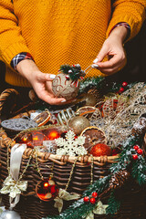 Young Woman with a Box Choosing Christmas Decorations in a Basket