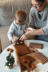 Little boy with mom decorate christmas gingerbread house together