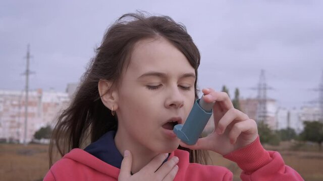 Suffering From Asthma With Inhaler. A Teen With Asthma Attack Use An Inhaler With Medication Outside.