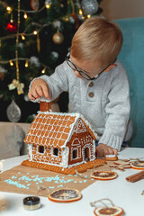 Little boy decorates christmas gingerbread house