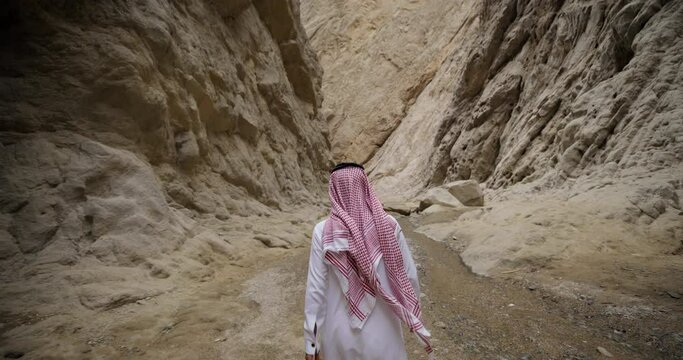 Tracking shot, Saudi Arabia man walks through river canyon in desert