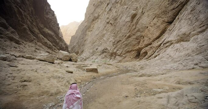 Wide, man walks through Saudi Arabia river canyon