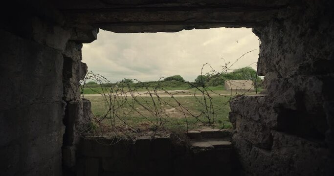 Dolly shot, view of barbed wire from inside Normandy bunker