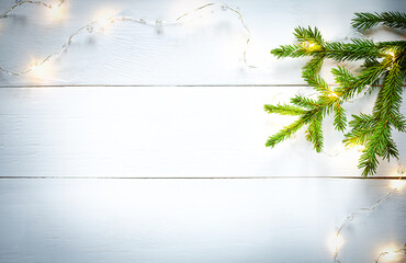 Christmas decoration green fir branches and yellow garland on white wooden board