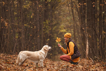 Portrait of a young woman with a dog in the autumn forest