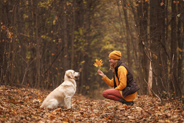 Portrait of a young woman with a golden retriever dog in the autumn forest