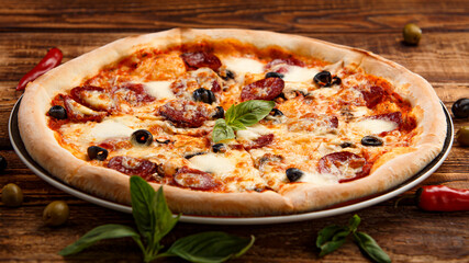 Pizza with meat and olives on a wooden background