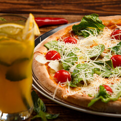 Caesar pizza with salad and tomatoes on wooden background