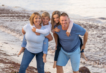 Happy family of four embracing, smiling and having fun by the sea. Outdoors family portrait