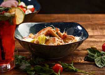 Caesar salad with chicken on a wooden background