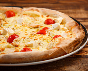 Pizza with cheese, spices and tomatoes on wooden background