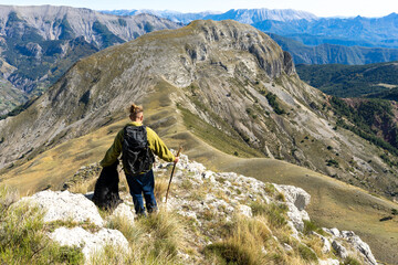 un homme avec un sac à dos avec son chien , face à un panorama en montagne