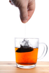 brewed a bag of black tea in a transparent mug on a wooden table.