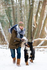 Woman playing with her dog in the snow