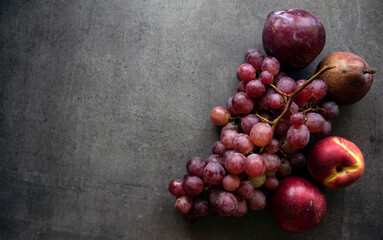 Fresh fruits on grey background with copy space. Top view photo of juicy grapes, pears and nectarines. Healthy eating concept. 