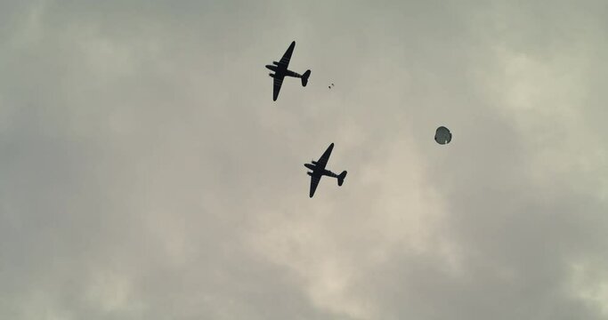 Low angle, soldiers parachute out of ww2 planes in Normandy