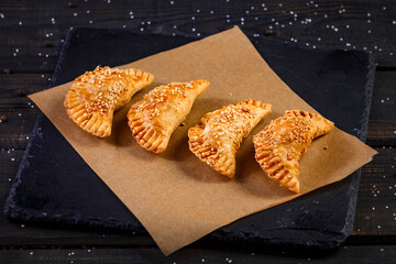 baked pies with meat and spices on a wooden background
