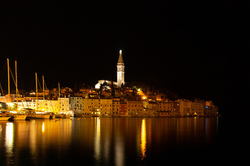 Fototapeta na wymiar Rovinj,Istria,Croatia.View of night city situated on the coast of Adriatic Sea.Popular tourist resort and fishing port.Old town with cobblestone streets, colorful houses and Church of St. Euphemia.