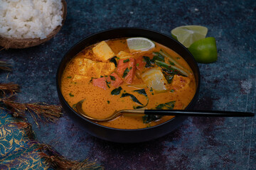 Vegan thai red curry with carrot, tofu and bock choy in black bowl, copy space