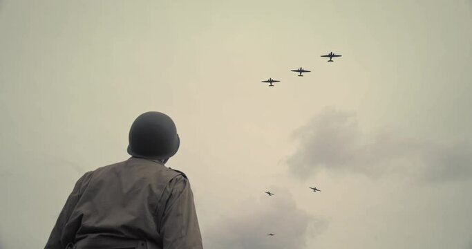 Low angle, ww2 soldier watches planes in field