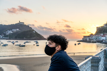 Fototapeta na wymiar 30-year-old man with a mask poses with the sea in the background