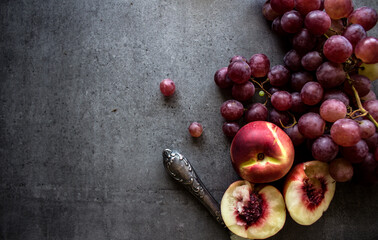 Fresh fruits on grey background with copy space. Top view photo of juicy grapes, pears and nectarines. Healthy eating concept. 