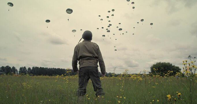 WW2 solders watch people parachute into Normandy, low angle