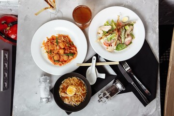 three-course set on a table in a restaurant, cafe menu. Business lunch from bowl ramen with chicken and egg, fresh caesar salad and pasta