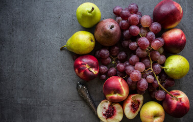 Beautiful fresh fruits on dark grey table: green grapes, nectarines, apricot. Summer fruits top view. 