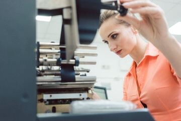 Worker woman putting new labels in printing machine