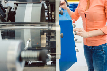 Woman pressing start button on label printing machine